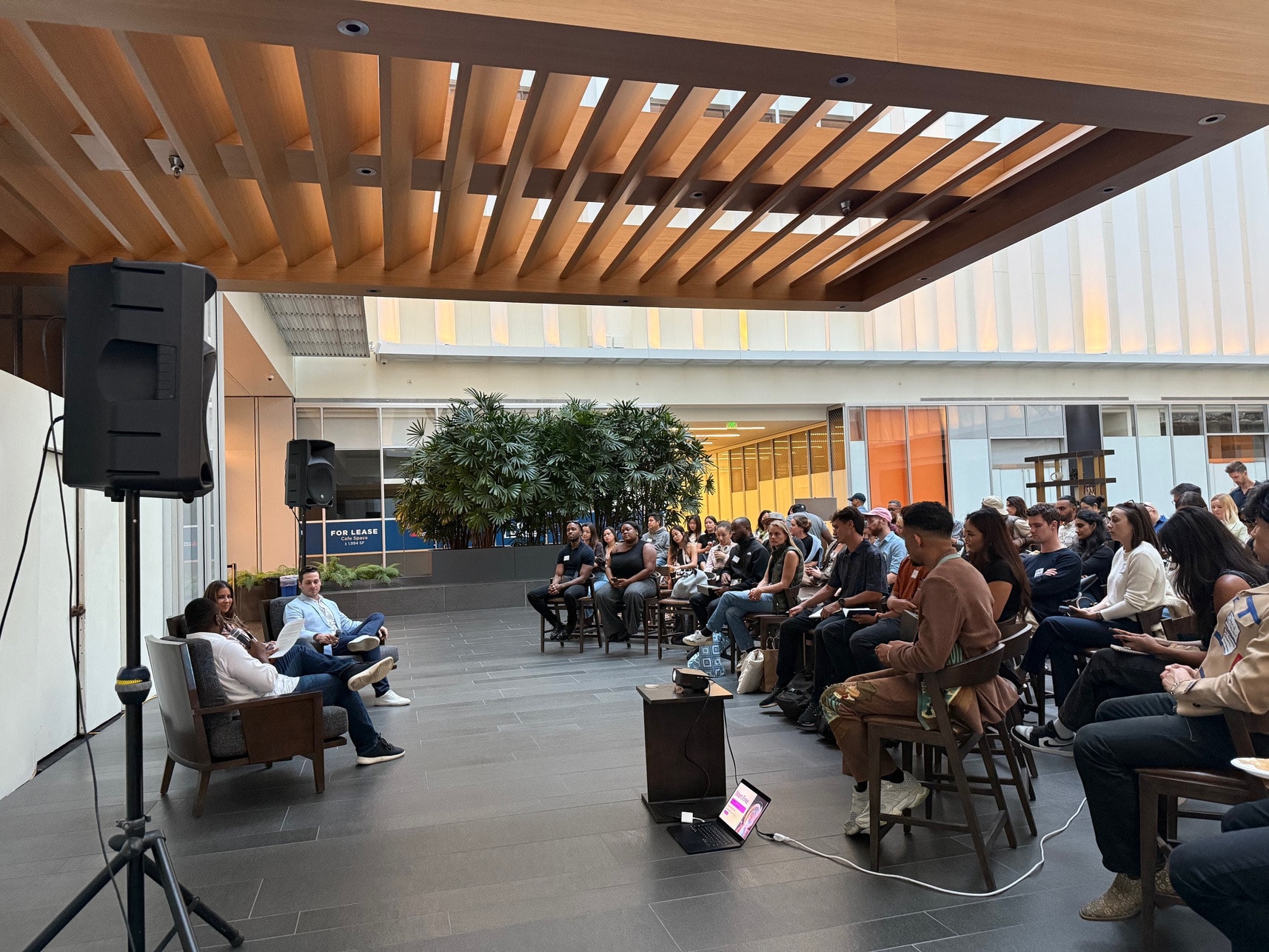 Speakers and a seated audience under the atrium canopy at an SF Tech Week session